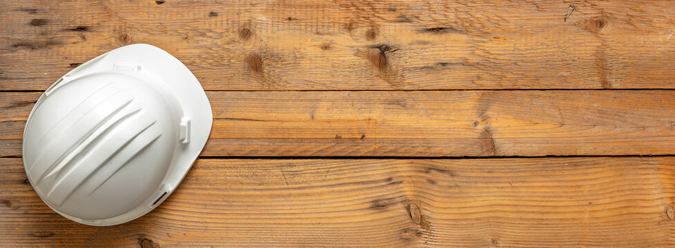 Safety helmet, white color hard hat, construction site engineer protective gear wooden background