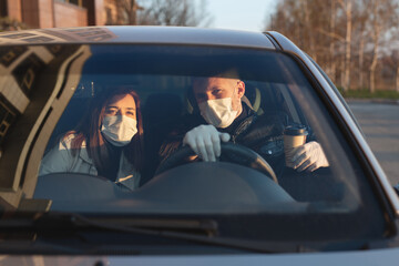 A man and a woman wearing medical masks and rubber gloves to protect themselves from bacteria and viruses while driving a car. masked men in the car. coronavirus, covid-19