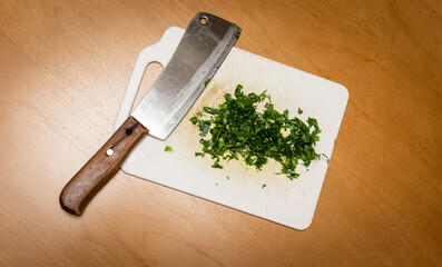 Perejil orgánico de huerta, picado con cuchilla sobre tabla