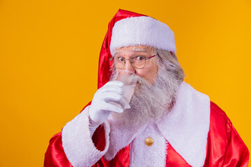Santa Claus drinking a glass of water on yellow background with space for text. Health and...