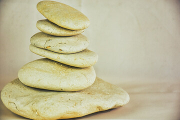 Fototapeta na wymiar cream colored smooth stones stacked on top of each other on vintage background