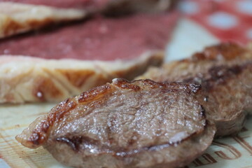 Peça de carne picanha inteira e com cortes crua e grelhada em frigideira