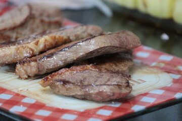 Peça de carne picanha inteira e com cortes crua e grelhada em frigideira