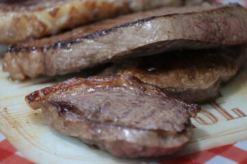 Peça de carne picanha inteira e com cortes crua e grelhada em frigideira