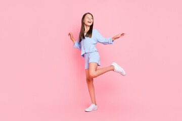 Photo of funny beautiful school girl dressed blue clothes smiling dancing isolated pink color...