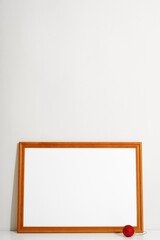 Horizontal frame mock-up with empty space for branding, picture or text and Christmas red ball toy against wall indoors. Minimalistic festive interior template