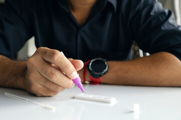 coronavirus infection prevention concept. man is holding an antigen (ATK) test kit in his hand with soft-focus and over light in the background.