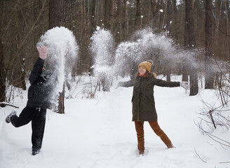 two joyful women in warm clothes have fun playing with snow outdoors in winter. fluffy snow throws up on each other. Hello winter, merry Christmas holidays, digital detox. Soft focus