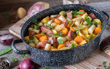 Pot with rustic stew cooked with pork meat and root vegetables