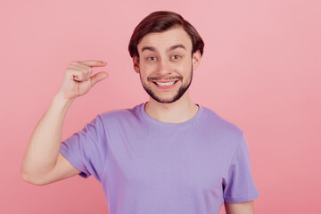 Photo of young man happy positive smile show tiny small size measures with fingers isolated over pink color background