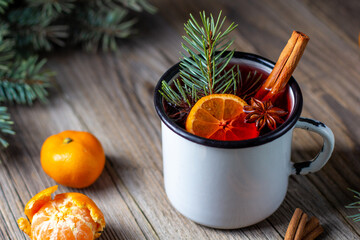 Traditional tasty mulled wine hot drink with mandarin apple spices and christmas tree in white cup