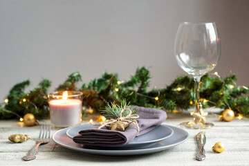 table setting for Christmas dinner with decorations on grey plate on white table. Holiday view with...