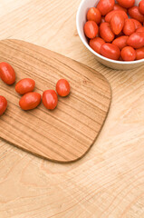 datterini tomatoes in a bowl with chopping board on a rustic wooden background