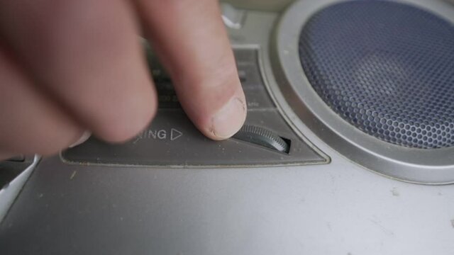 Male wrinkled finger turning vintage tuner wheel for searching frequency. Retro and ancient audio equipment concept.