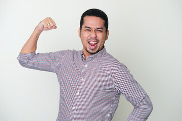 Adult Asian man showing his arm muscle with excited face expression