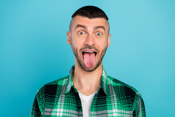 Photo of funky happy positive young man stick out tongue funny face crazy enjoy isolated on blue color background