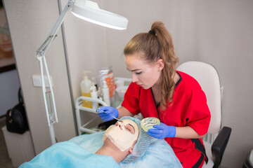 The girl at the beautician makes spa treatments, massage, facial cleansing and a mask for the skin....