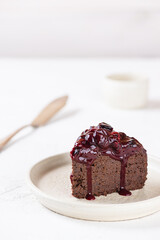 Piece of vegan chocolate cake with berry jam on a wooden board. Sugar, gluten and lactose free.