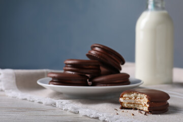 Tasty choco pies and milk on white wooden table