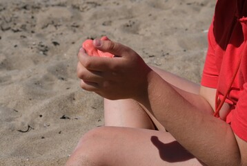 The girl has red slime in her hands. The girl is always enthusiastic about playing with slime, even on the beach playing with slime calms her down.