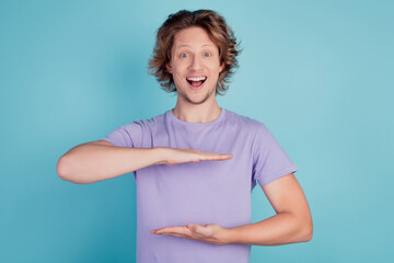 Photo of young man happy positive smile amazed excited show hands measure size length isolated over teal color background