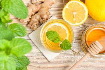 Tea with lemon, ginger root, honey and mint leaves top view on wooden background	