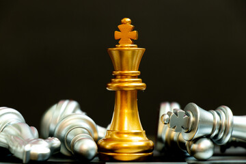 Gold king chess piece win over lying down silver team on black background