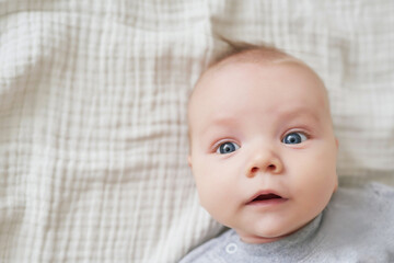 Newborn toddler boy lies and plays with educational toys. Happy motherhood and fatherhood. Maternity hospital and clinic. Father and mother day. Early childhood development