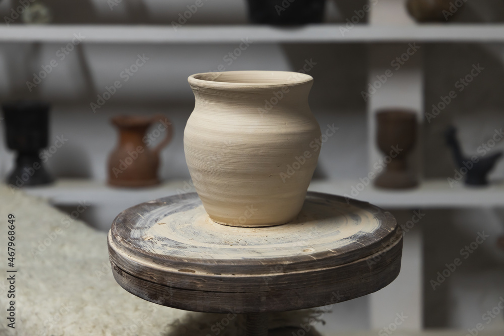 Wall mural white clay pot stands on a pottery wheel, closeup