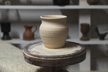 White clay pot stands on a pottery wheel, closeup - obrazy, fototapety, plakaty