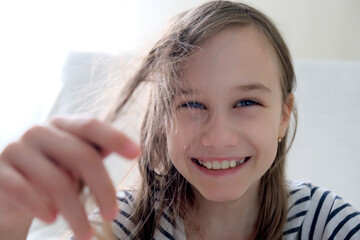 Smiling girl holding tangled hair in her hand