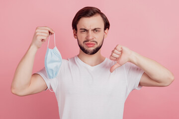 Portrait of exhausted guy take off respirator make thumb down dislike sign on pink background
