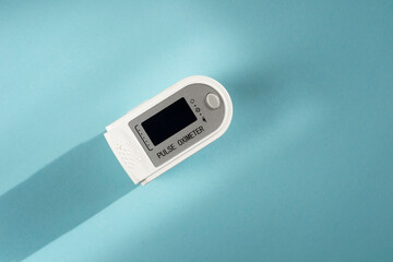 Pulse oximeter for measuring the level of oxygen in the blood on a blue background. Empty space for text. 