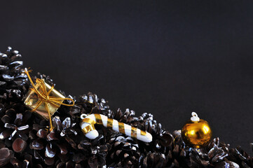 Black and golden christmas background for greeting card with cones and christmas toys