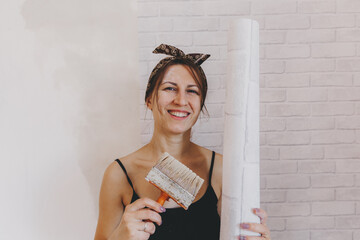 Young woman glues wallpaper at home. girl glues wallpaper in the form of a brick. repair.