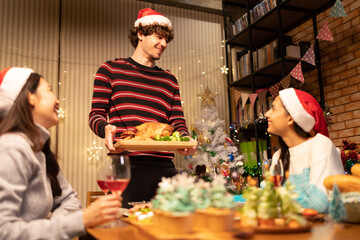 Group of Friends Enjoying Christmas Drinks  at home.Winter holidays concept.Happy friends are having dinner at home. Celebration holiday and togetherness near tree.Party with glasses of champagne.