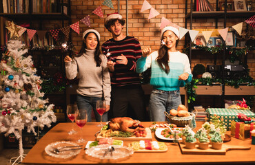 Group of Friends Enjoying Christmas Drinks  at home.Winter holidays concept.Happy friends are having dinner at home. Celebration holiday and togetherness near tree.Party with glasses of champagne.