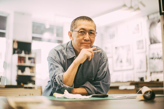 Senior craftsman with hand on chin at workshop