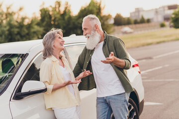 Photo of funny beautiful retired couple wear casual clothes driving car talking smiling outside urban city street