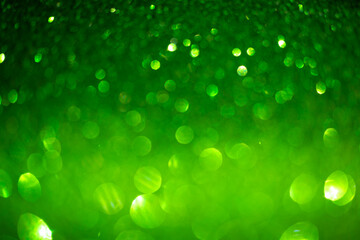 Green glittering background. Christmas sparkles, texture with bokeh and shiny lights