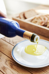 Olive Oil Pouring into a Saucer Close Up with Bread - obrazy, fototapety, plakaty