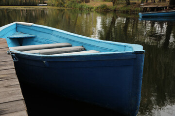 Fototapeta na wymiar Light blue wooden boat on lake near pier, closeup