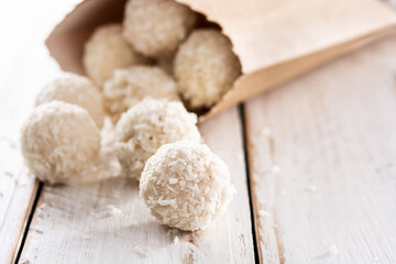 Homemade coconut balls on white wooden table