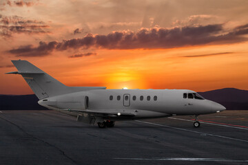 Fototapeta na wymiar Modern corporate business jet at the airport apron on the background of a picturesque sunset