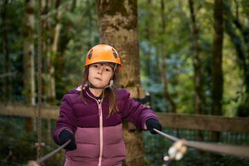 adventure climbing high wire park - kids on course in mountain helmet and safety equipment