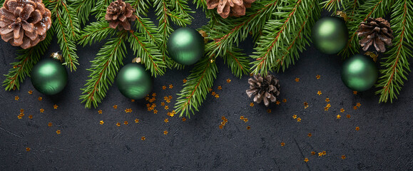 Christmas Decoration. Holiday Decorations with baubles, fir branches and present on dark black background. Border design. Top view.