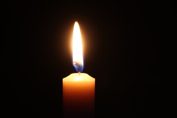 The flame of one candle on a horizontal black background candle in the middle is a calm flame of a candle