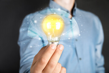 Glow up your ideas. Man holding light bulb on dark background, closeup