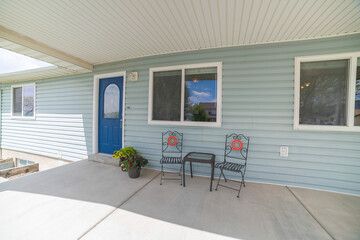Porch of a house with blue front door with ornate glass panel