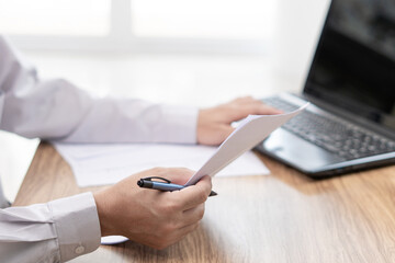 A man hold document and pen in hand use laptop computer about car repairs and use working on table in office